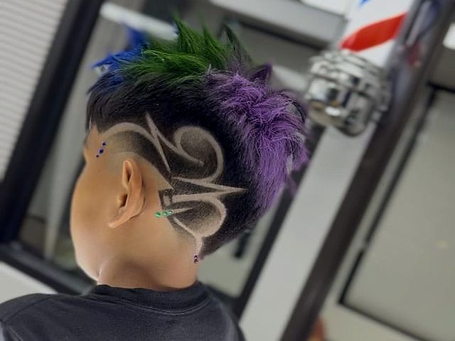 Niño con mohawk teñido de verde y morado y un diseño trazado en el lateral.