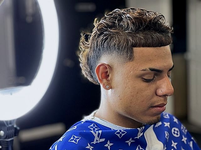 Cliente con rizos con textura arriba y fade en los lados, junto al aro de luz.
